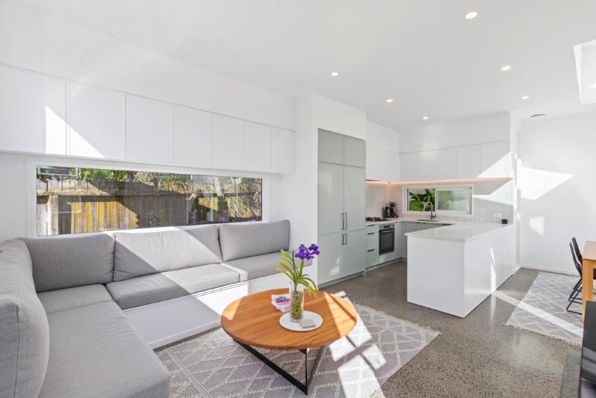 Small modern kitchen in corner of living area all in white