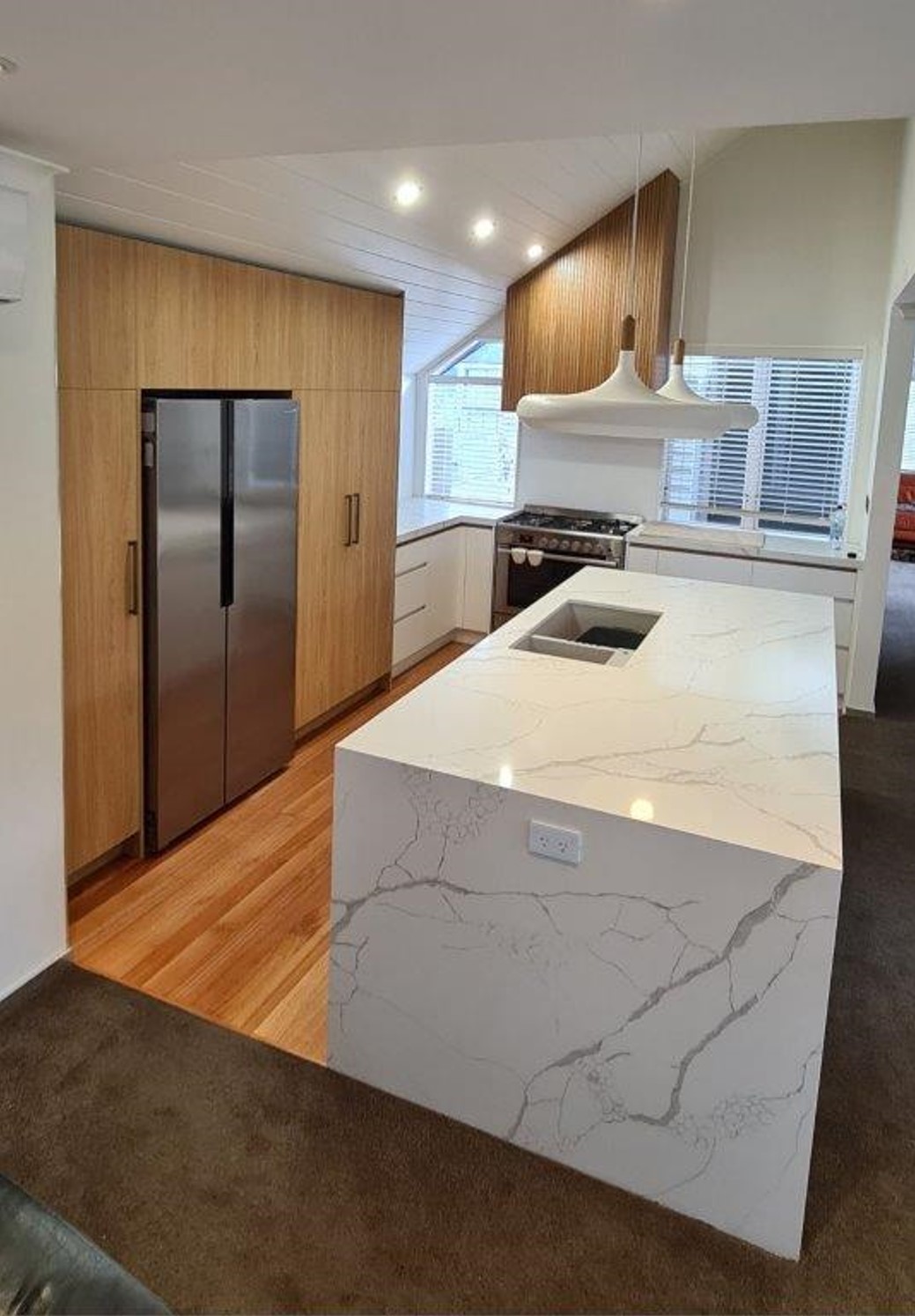 Modern kitchen with wood paneling and white marble island bench